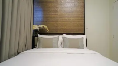 a bed with white sheets and pillows next to a window at Currency Serviced Suites in Manila