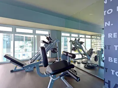a gym with several tread machines and a mirror at Currency Serviced Suites in Manila