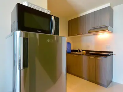 a microwave on top of a refrigerator in a kitchen at Currency Serviced Suites in Manila