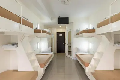 a room with white shelves and a tv on a wall at Selah Garden Hotel Manila in Manila