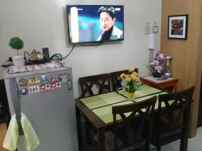 a kitchen with a table and a television on a wall at 1Bedroom with Balcony in Manila