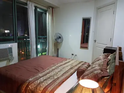 a bedroom with a bed and a large window at ORTIGAS 2 Br Corner Unit With 2 Queen Across Shangrila in Manila