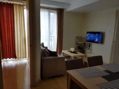 a living room with a couch and a television at ORTIGAS 2 Br Corner Unit With 2 Queen Across Shangrila in Manila