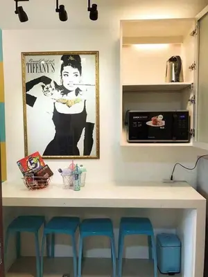 a kitchen with a counter with stools and a microwave at Tiffany Room At Shell Residences in Manila