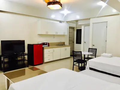 a room with two beds and a kitchen with a red refrigerator at RESIDENCIA SAN VICENTE - PASAY -Budget Hotel in Manila