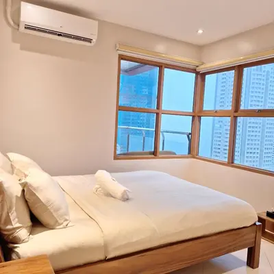 a bedroom with a large bed with windows at MANILA BAYVIEW RENTAL- LUXURY AND SUPERIOR 1 - 5 BEDROOM CONDOS WITH BALCONY POOL BAYVIEWS NETFLIX - Housekeeping Available- in Manila