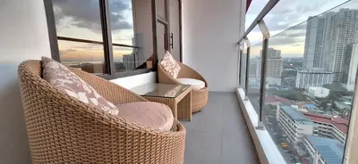 a balcony with wicker chairs and a table and windows at MANILA BAYVIEW RENTAL- LUXURY AND SUPERIOR 1 - 5 BEDROOM CONDOS WITH BALCONY POOL BAYVIEWS NETFLIX - Housekeeping Available- in Manila