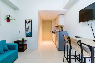 a living room with a blue couch and a kitchen at Linda's Condo in Manila