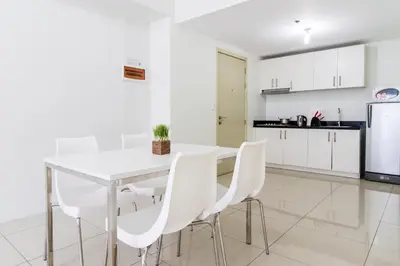 a white kitchen with a white table and white chairs at Linda's Condo in Manila