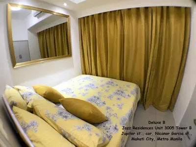 a bedroom with a bed with pillows and a mirror at Jazz Makati Luxury Apartment in Manila