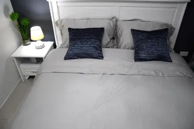 a white bed with two blue pillows on it at Jazz Makati Luxury Apartment in Manila