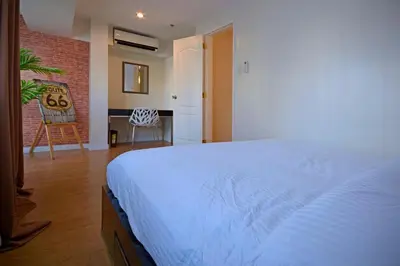 a bedroom with a white bed and a brick wall at Victoria SOHO Suites in Manila