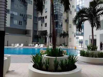a swimming pool with palm trees and a building at Victoria SOHO Suites in Manila