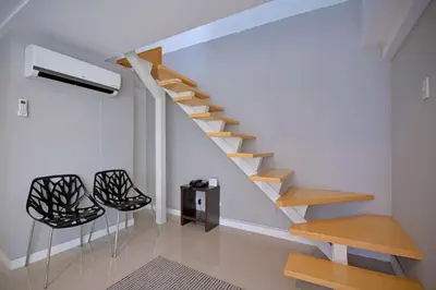 a staircase in a living room with two black chairs at Victoria SOHO Suites in Manila