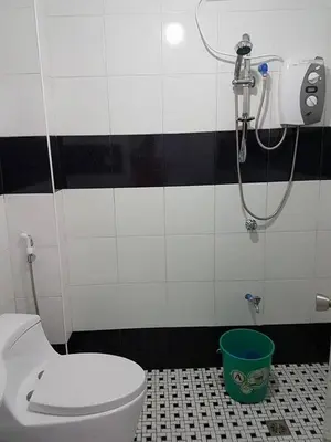 a bathroom with a shower and a toilet and a bucket at N&J Lopez Lodging House in Manila