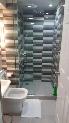 a bathroom with a toilet and a glass shower at Burgundy McKinley Place Service Apartment in Manila