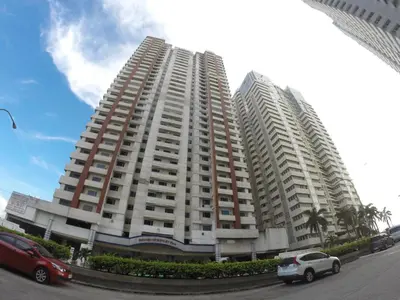 a large apartment building with cars parked in front of it at Burgundy McKinley Place Service Apartment in Manila