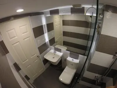 a small bathroom with a toilet and a sink at Burgundy McKinley Place Service Apartment in Manila