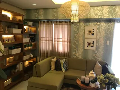 a living room with a green couch and a chandelier at Sorrel Residences Condo Apartment by Fe in Manila