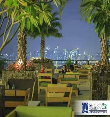 a group of people sitting at a restaurant with palm trees at Sorrel Residences Condo Apartment by Fe in Manila