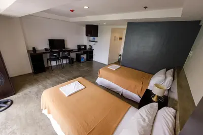 a hotel room with two beds and a television at 5880 Enriquez Residences in Manila