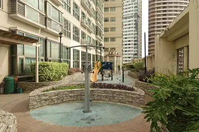 a fountain in the middle of a city with buildings at Modern Asian Condo at Forbeswood Parklane The Fort BGC in Manila