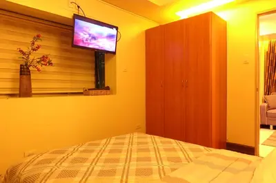 a bedroom with a bed and a flat screen tv at Modern Asian Condo at Forbeswood Parklane The Fort BGC in Manila