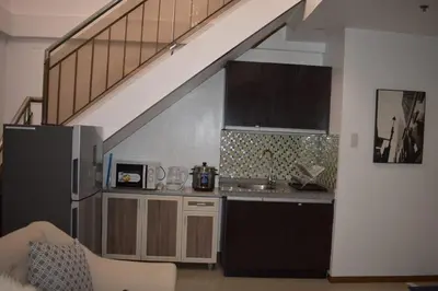 a kitchen with a sink and a kitchen under a staircase at Affordable Makati APT in Manila