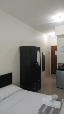 a bedroom with a white bed and a black cabinet at Affordable Makati Serviced Apartments in Manila