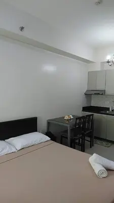 a bedroom with a bed and a table and a kitchen at Affordable Makati Serviced Apartments in Manila