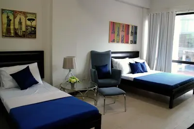 a hotel room with two beds and a chair at Food District Hostel - Ortigas Kapitolyo in Manila