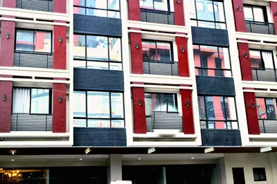 a tall red and white building with black windows at Food District Hostel - Ortigas Kapitolyo in Manila