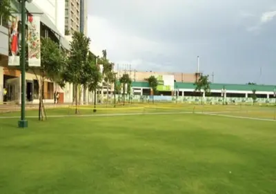 a large green field with tennis courts in front of a building at Food District Hostel - Ortigas Kapitolyo in Manila