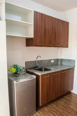 a kitchen with wooden cabinets and a sink and a dishwasher at Titan Condo at Studio City Tower 1 Alabang in Manila