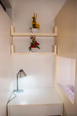 a room with shelves and a desk with a lamp at Titan Condo at Studio City Tower 1 Alabang in Manila