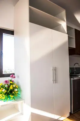 a white cabinet in a kitchen with a vase of flowers at Titan Condo at Studio City Tower 1 Alabang in Manila