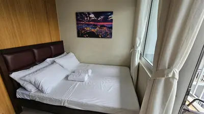 a small bed in a room with a window at The Palawanos Home at Shell Residences in Manila