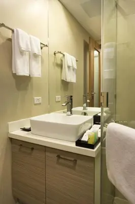 a bathroom with a white sink and a mirror at Valero Grand Suites by Swiss-Belhotel in Manila