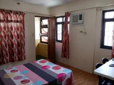 a room with a bed and a table and windows at Budget Studio Unit in Makati in Manila