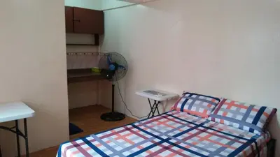 a small bedroom with a bed and a fan at Budget Studio Unit in Makati in Manila