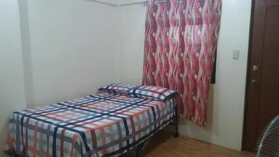 a small room with a bed and a curtain at Budget Studio Unit in Makati in Manila