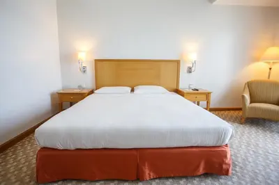 a bedroom with a large bed and a chair at The Linden Suites in Manila