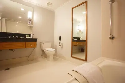 a bathroom with a toilet and a sink and a mirror at The Linden Suites in Manila