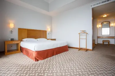 a hotel room with a large bed and a desk at The Linden Suites in Manila