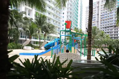 a playground with a slide in a park with palm trees at Maui Condotel Azure Residence in Manila