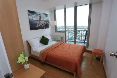 a bedroom with a bed and a large window at Maui Condotel Azure Residence in Manila