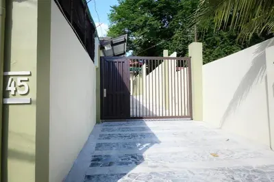 a black gate on a white wall next to a walkway at The Leaf House in Manila