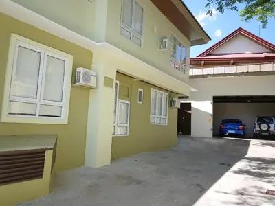 a yellow house with a garage and a car at The Leaf House in Manila