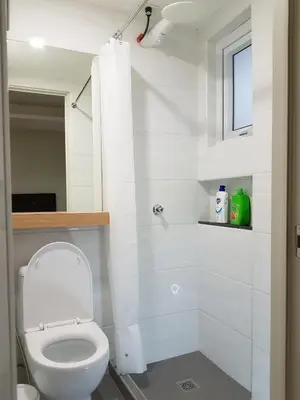 a white bathroom with a toilet and a shower at The Leaf House in Manila