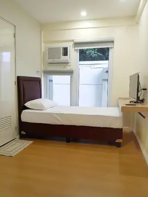 a bedroom with a bed with a microwave and a window at The Leaf House in Manila